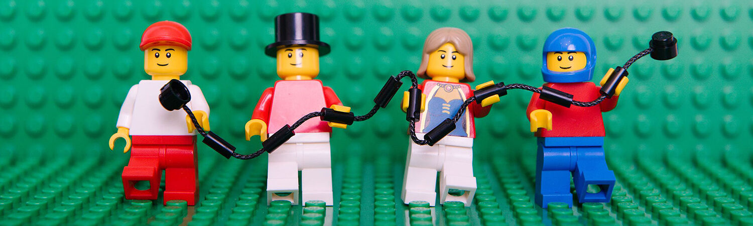 LEGO SERIOUS PLAY-banner-1500 4 mini LEGO figures in a row in different outfits holding a LEGO style rope